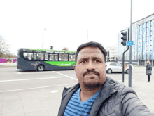 a man taking a selfie in front of a bus that says ' stourbridge ' on it