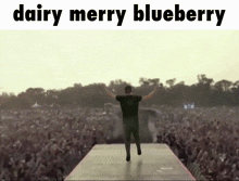 a man stands on a stage in front of a crowd with the words " dairy merry blueberry " above him