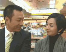 a man in a suit and tie stands next to a woman in a store with a sign that says hong kong