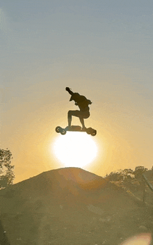 a silhouette of a person on a skateboard in the air at sunset