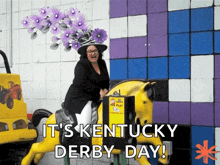 a woman wearing a purple hat is riding a yellow horse with the words it 's kentucky derby day below her