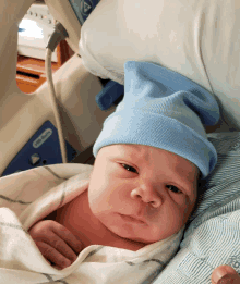 a baby wearing a blue hat is laying in a hospital bed next to a little tikes device