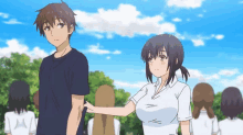 a man and a woman are standing next to each other in a park . the woman is holding the man 's arm .