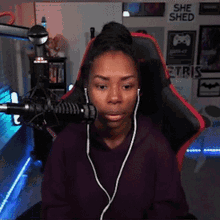 a woman wearing headphones is sitting in front of a microphone in a room with a sign that says she shed