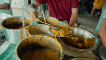 a man in a red shirt is scooping food out of a bowl with a spoon