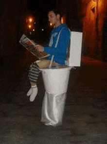 a man in a toilet costume is reading a newspaper while sitting on a toilet .