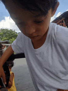 a young boy wearing a white shirt is looking down