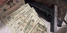 a stack of 20 dollar bills next to a gun and a louis vuitton purse