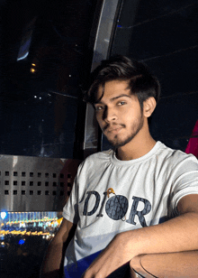 a young man wearing a white dior t-shirt looks at the camera