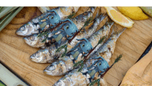 a bunch of fish on a wooden cutting board with a lemon slice in the background