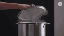 a person is holding the lid of a pot of boiling water .