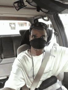 a man wearing a bandana and a face mask is sitting in the back seat of a car