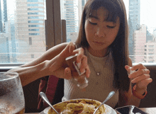 a woman is sitting at a table with a bowl of food and a glass of beer in front of her