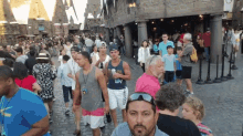 a man wearing sunglasses stands in a crowd of people in front of a building that says ' harry potter ' on it