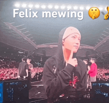 a man in a hoodie stands in front of a crowd with the words felix mewing written above him