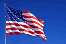 a large american flag is flying in the wind against a blue sky