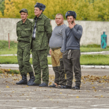 four men in military uniforms are standing in a parking lot