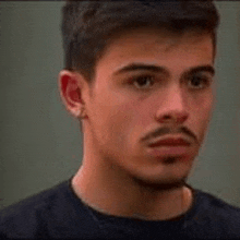 a close up of a man 's face with a beard and mustache wearing a black shirt .