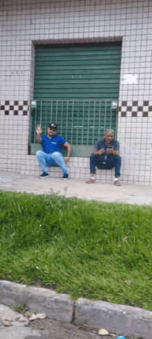 two men sit on a sidewalk in front of a building with the number 5 on it