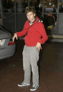 a young man wearing a red hoodie and grey pants