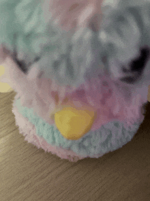 a stuffed animal with a yellow beak is on a wooden table