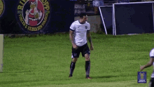 a soccer player stands on the field in front of a sign that says ' torcer e beber sem violência '