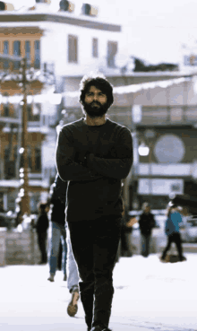 a man with his arms crossed walks down a street