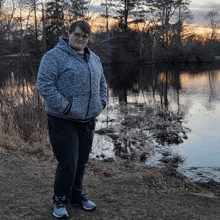 a man stands in front of a lake at sunset