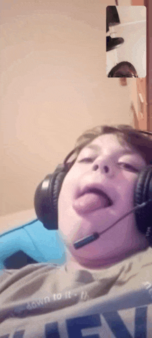 a boy wearing headphones is sticking his tongue out while talking on a video call .