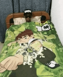 a man is laying in a bed with a ben 10 blanket on it .