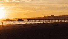 a sunset over the ocean with a pier in the distance