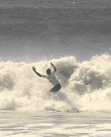 a surfer wearing a shirt that says ' sydney ' on it is riding a wave