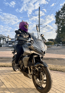 a woman wearing a purple helmet is sitting on a motorcycle