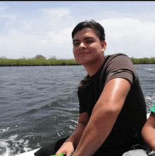 a man in a black shirt is smiling while sitting on a boat