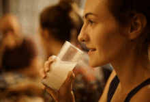 a woman is drinking a glass of milk .