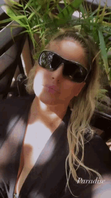 a woman wearing sunglasses and a black top with the word paradise written on the bottom