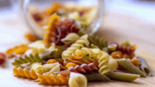 different types of pasta are spilling out of a jar