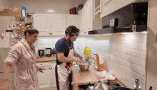 a man and a woman are preparing food in a kitchen and the man is wearing an apron that says " chef " on it