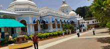 a man with a cane walks in front of a very large building