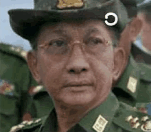 a man in a military uniform with glasses and a hat is looking at the camera .