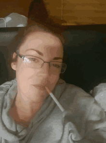 a woman with glasses is smoking a cigarette in her mouth