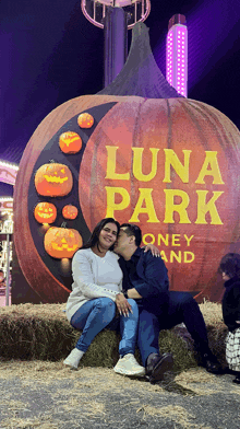 a man and woman kiss in front of a large pumpkin that says luna park