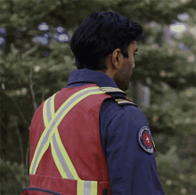 a man wearing a red vest and a blue shirt has a patch on his sleeve that says emergency services