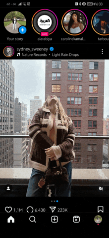 a woman is standing on a balcony in front of a building on a phone