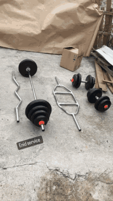 a set of barbells and dumbbells are laying on the ground with a label that says enid service on it