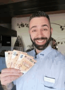 a man with a beard is holding a bunch of money in his hands and smiling .