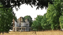 a house is surrounded by trees in a field