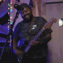 a man playing a guitar in front of a microphone with a sign on the wall that says no smoking