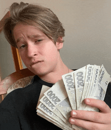 a young man is holding a stack of 2000 bills in his hand