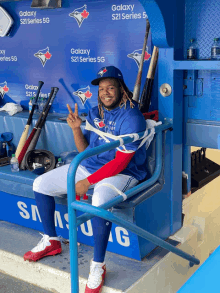 a blue jays player sits in a dugout with a galaxy s21 series 5g advertisement behind him